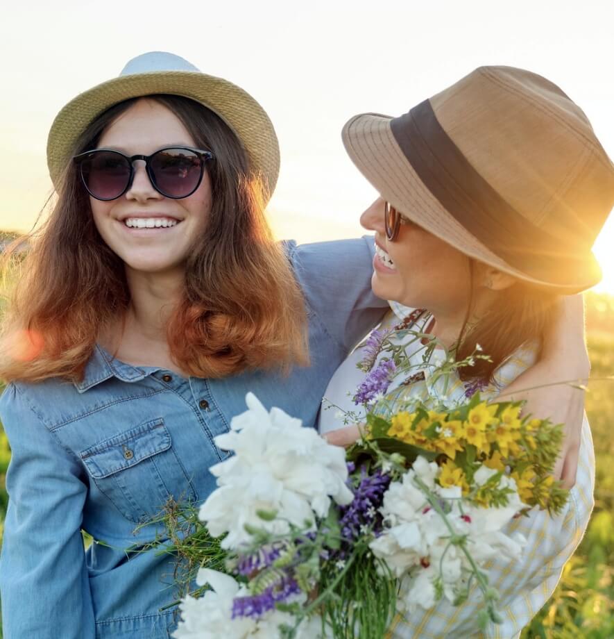 Two women smiling with the sun setting behind them.